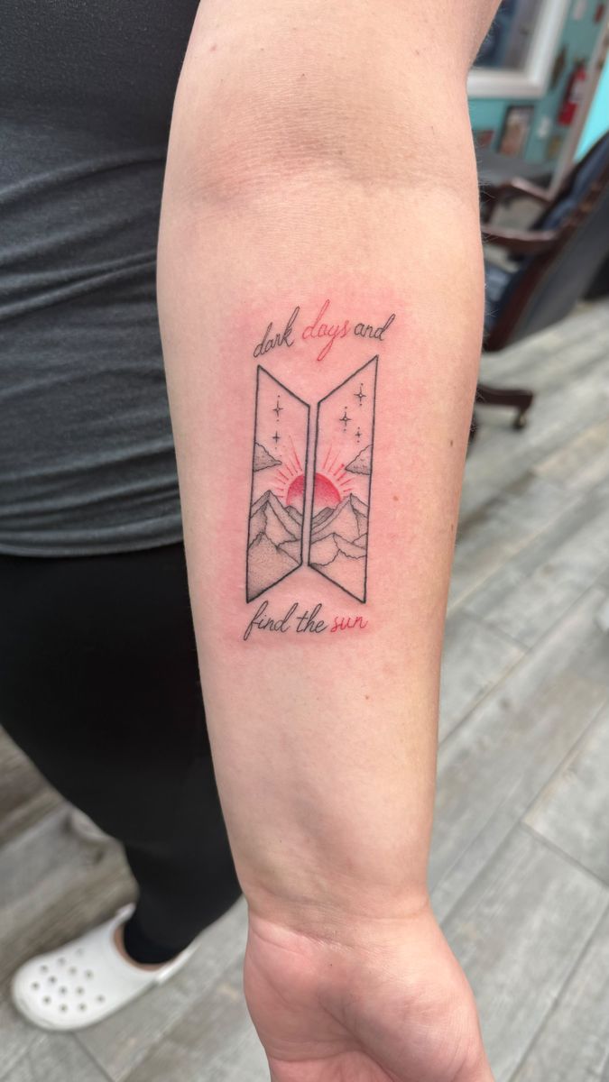 Mountains and a red sun framed by “dark days” and “find the sun” script on the forearm — fine line tattoo by Aline at Diamond Mind Tattoo, Buzzards Bay