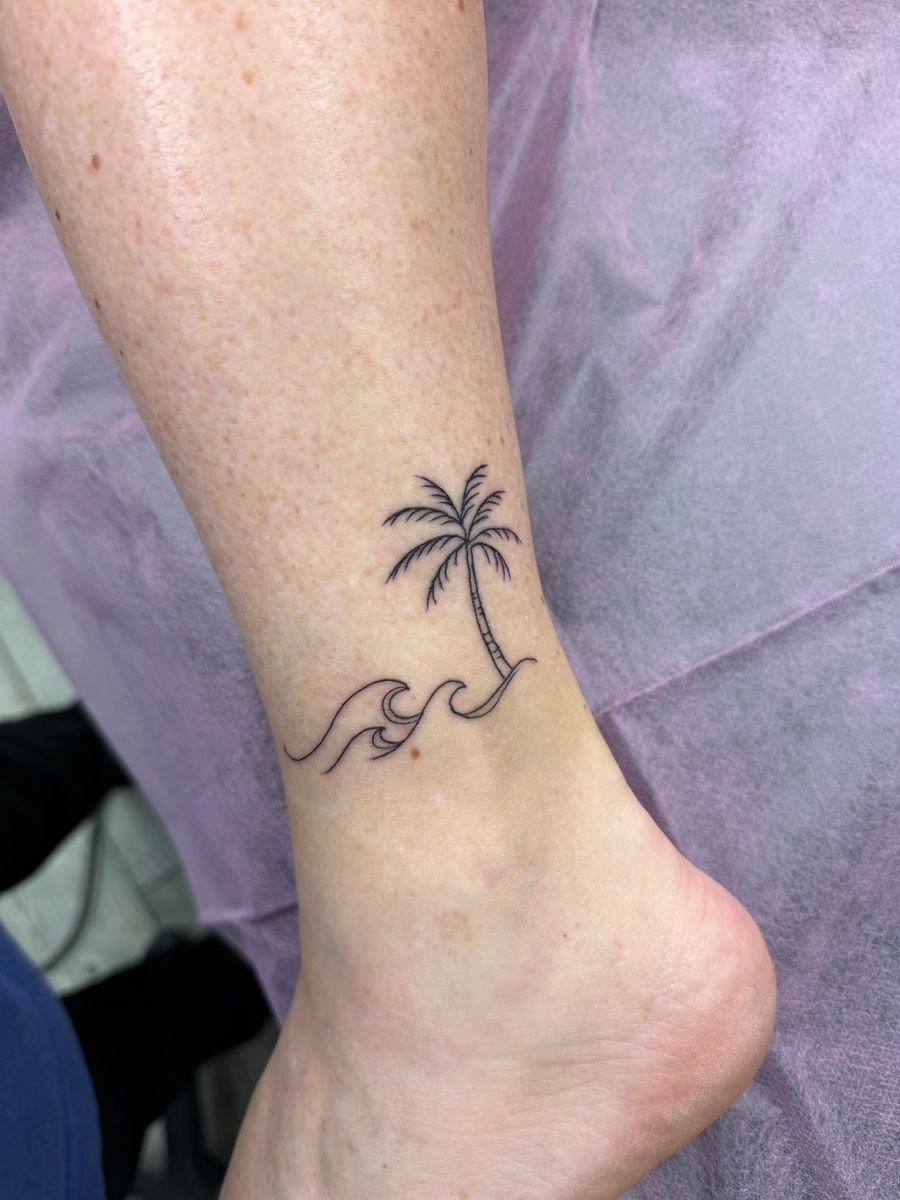 Palm tree and ocean waves on the ankle — fine line tattoo by Aline at Diamond Mind Tattoo, Buzzards Bay