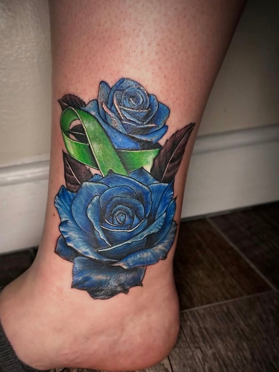 Two blue roses with a green ribbon on the ankle, color realism tattoo by Brendon at Diamond Mind Tattoo, Buzzards Bay