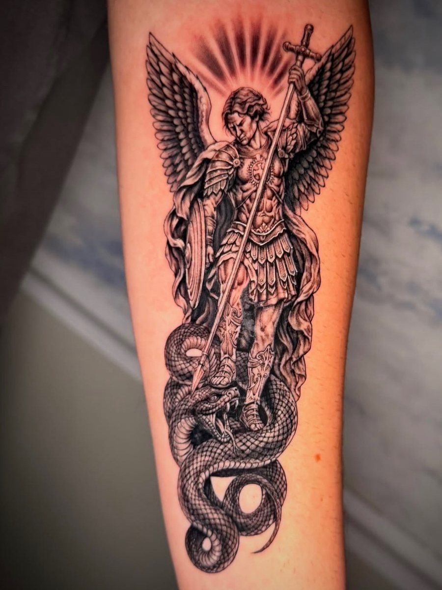 St. Michael the archangel with wings and a spear standing over a serpent on the forearm, black and grey realism tattoo by Brendon at Diamond Mind Tattoo, Buzzards Bay