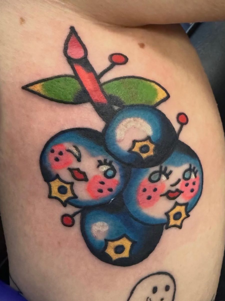 Cluster of blueberries with cute faces and green leaves on the upper arm, American Traditional tattoo by Chris at Diamond Mind Tattoo, Buzzards Bay