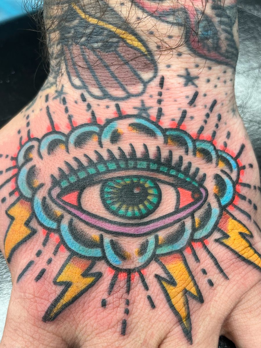 Eye in a blue cloud with lightning bolts on the back of the hand, American Traditional tattoo by Chris at Diamond Mind Tattoo, Buzzards Bay
