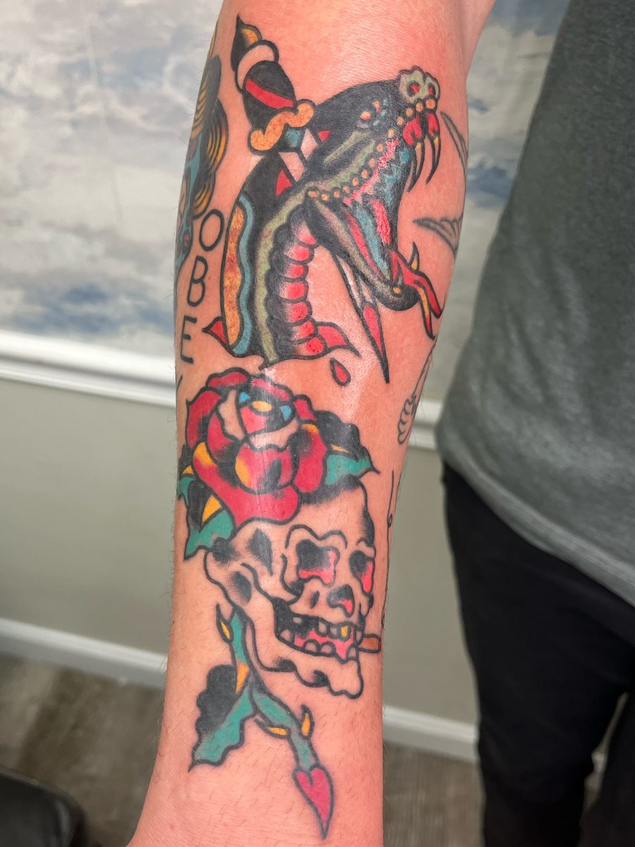 Snake head with a dagger above a rose and a skull on the forearm, American Traditional tattoo by Chris at Diamond Mind Tattoo, Buzzards Bay