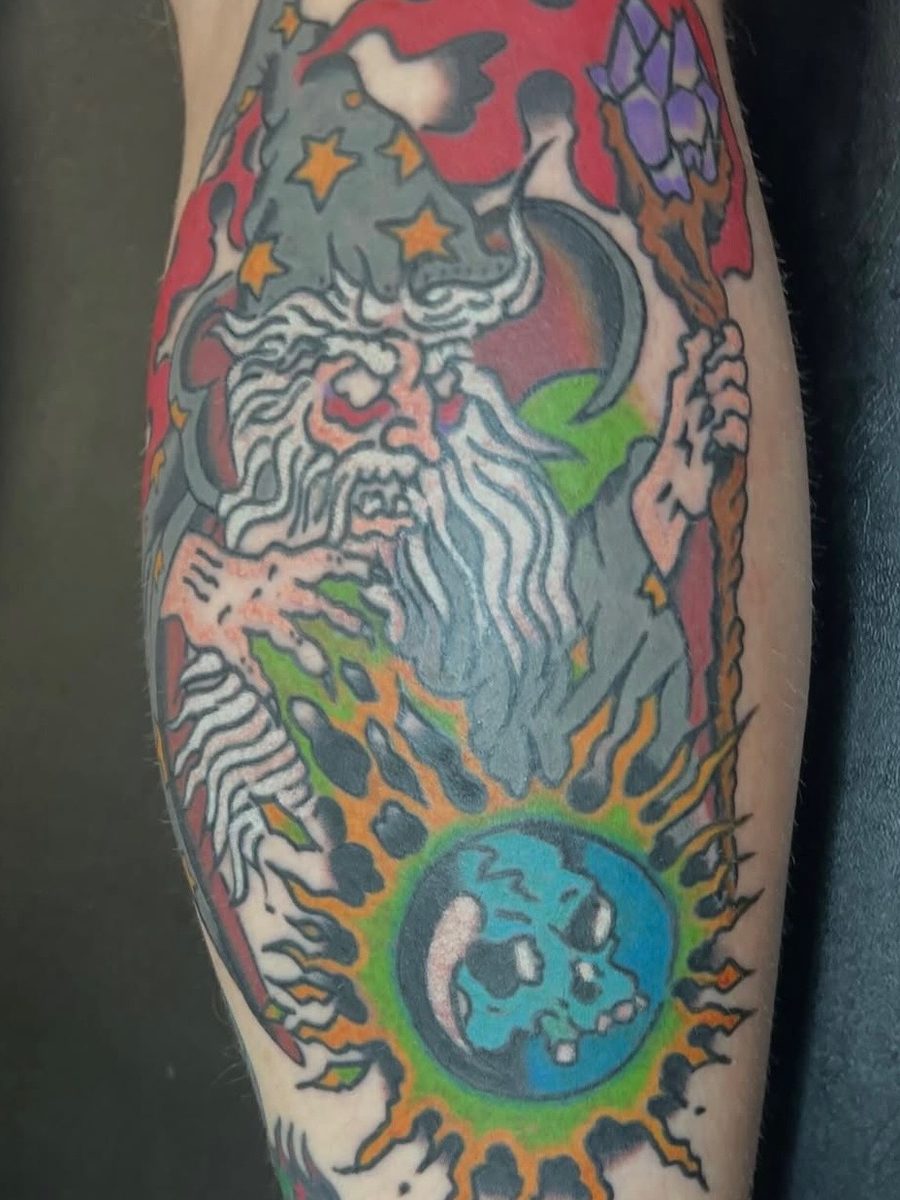Wizard with a starry hat and a crystal staff over a blue skull sun on the calf, American Traditional tattoo by Chris at Diamond Mind Tattoo, Buzzards Bay